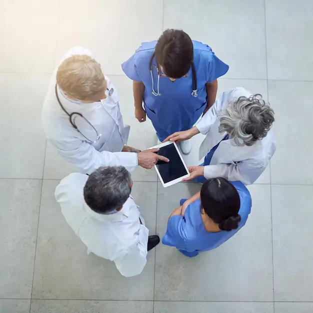 Medical professionals collaborating while reviewing data on a tablet.