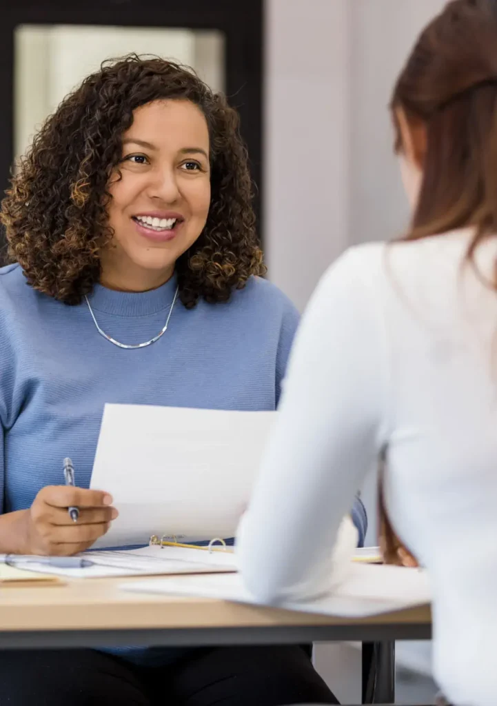 Smiling recruiter holding resume during job interview discussion.