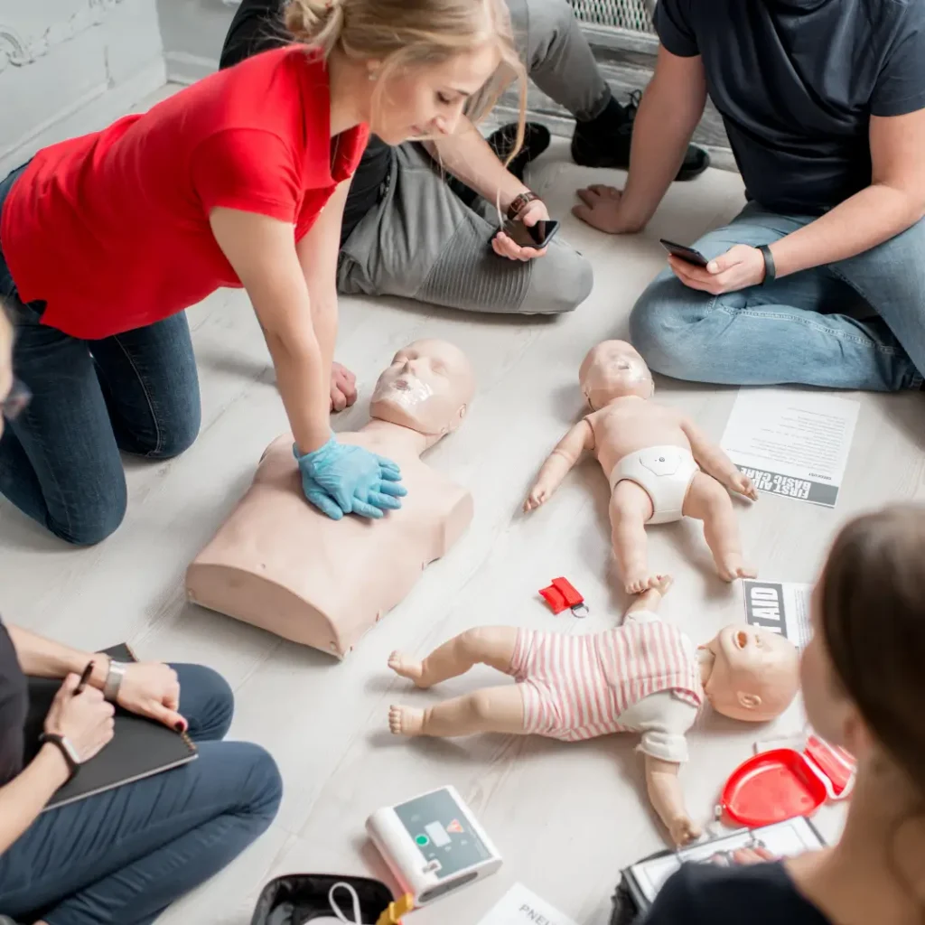 CPR training session with adult and infant manikins and AED devices.